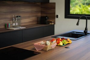 A modern kitchen with a wooden countertop, a fruit tray, and a coffee machine. - Villa Kynoa 4-Star (Saint-François)
