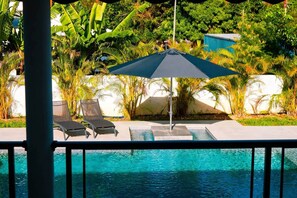 A poolside area with lounge chairs and a shaded umbrella. - Villa Kynoa 4-Star (Saint-François)