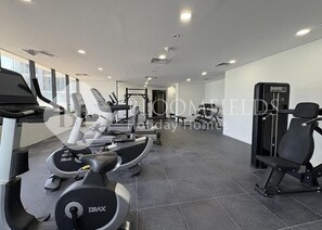 A gym with treadmills, elliptical machines, and weightlifting equipment. - Bloomfields Vista Elegance 1Br Al Maryah (Abu Dhabi)