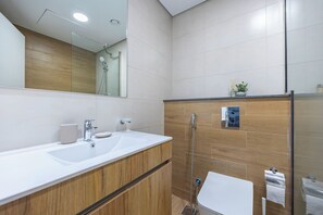 A modern bathroom with a large mirror, two sinks, a shower, and a toilet. - Bloomfields Vista Elegance 1Br Al Maryah (Abu Dhabi)
