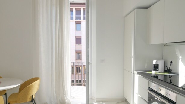 A modern kitchen with white cabinets, a built-in oven, and a coffee maker on the countertop.