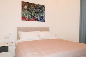 A bedroom with a bed, a nightstand, a lamp, and a painting on the wall.