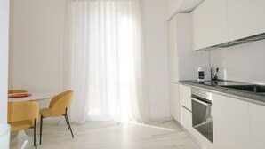 A modern kitchen with white cabinets, a stainless steel countertop, and a built-in oven.