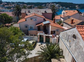 Un edificio residencial con techo de tejas rojas, un pequeño jardín y vista a un pueblo costero.