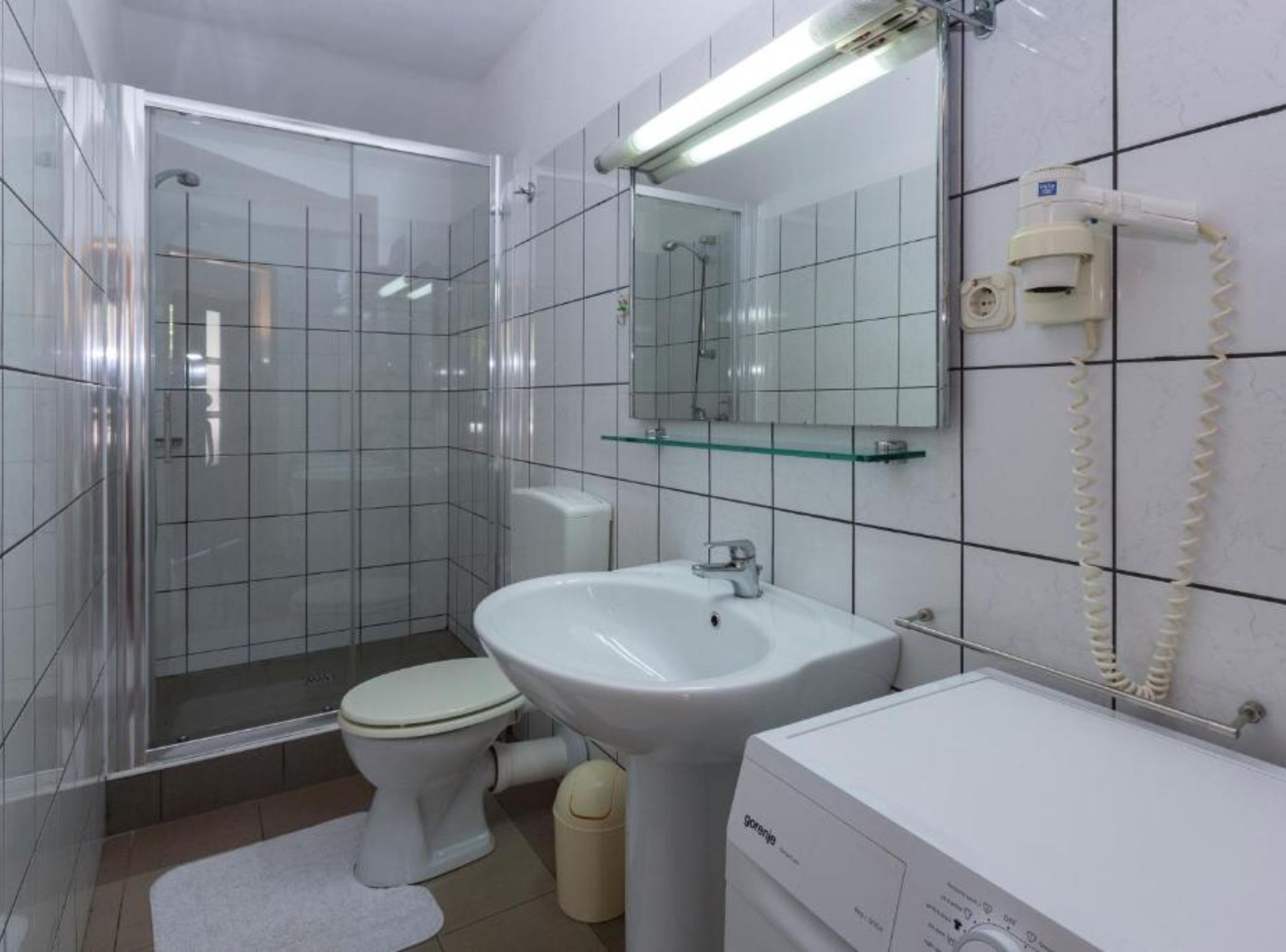 Un baño moderno con cabina de ducha de vidrio, inodoro, lavabo y espejo.