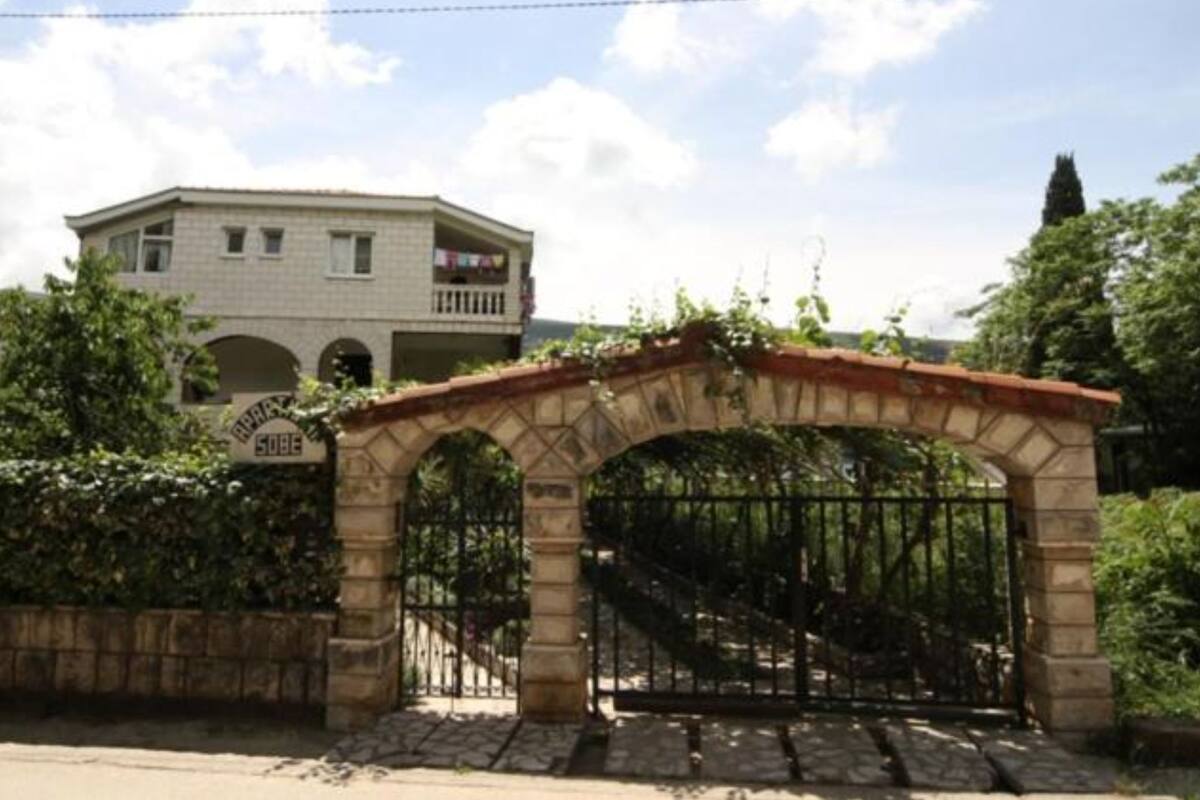 A stone archway leading to a gated entrance with a building in the background.