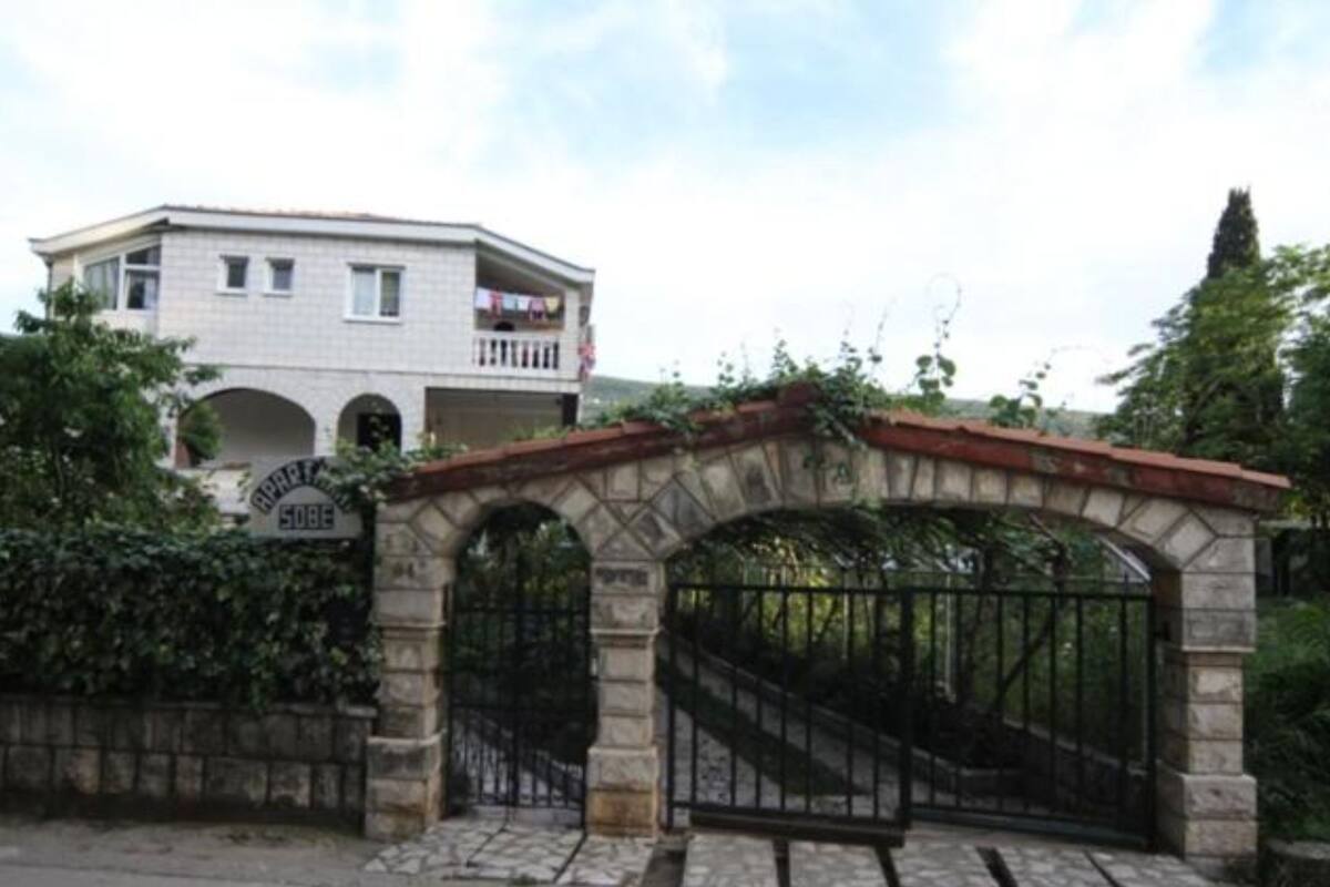A building with a stone archway and a metal gate, surrounded by greenery.