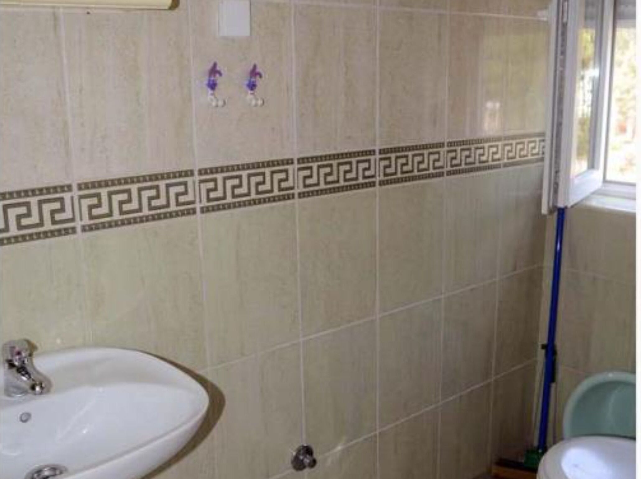 Une salle de bain avec un lavabo, des toilettes et une fenêtre.