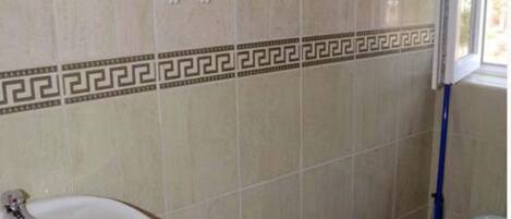 Une salle de bain avec un lavabo, des toilettes et une fenêtre.