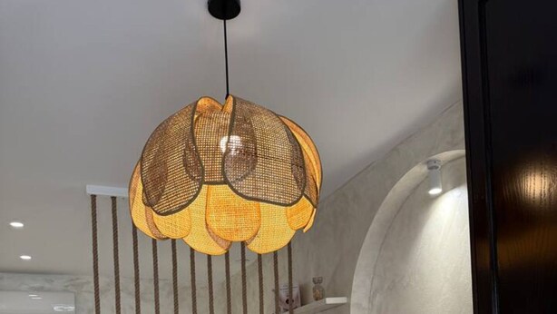 Ein modernes Schlafzimmer mit einem Bett, einem weißen Konsolentisch, einer Couch und einer außergewöhnlichen gewebten Leuchte.