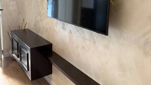 Ein modernes Wohnzimmer mit einem flachbildfernseher an der Wand, einer eingebauten Sitzbank und Holzboden.