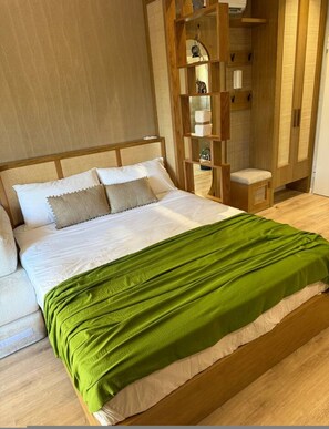A neatly made bed with a green blanket, a wooden headboard, and a small wooden stool beside it. - Luvra 1 Dh rmi Spacious Balcony Hideaway (Himarë)