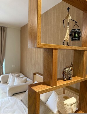 A hotel room with a wooden shelf unit displaying a lamp, an elephant figurine, and a decorative item. - Luvra 1 Dh rmi Spacious Balcony Hideaway (Himarë)