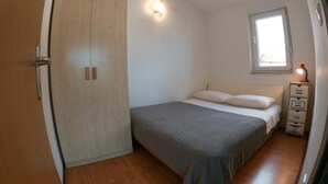 A bedroom with a bed, a wardrobe, a nightstand, and a window. - Sanja Apartments Posedarje (Posedarje)