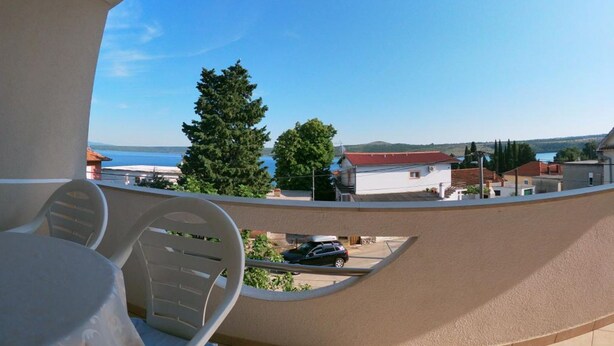 A balcony with a view of a body of water, a tree, and a building. - Sanja Apartments Posedarje (Posedarje)
