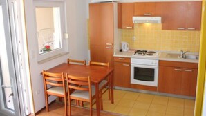 A compact kitchen with wooden cabinets, a stove, and a sink. - Sanja Apartments Posedarje (Posedarje)