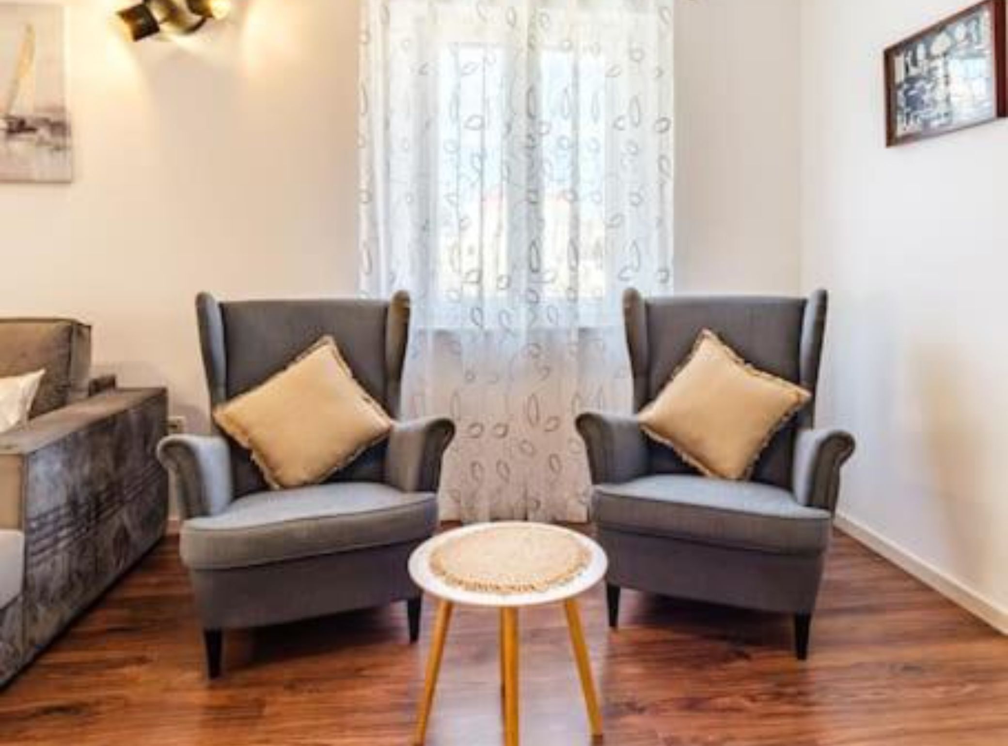 A living room with two grey armchairs, a small round table, and a patterned curtain.
