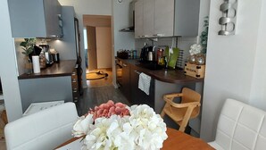 Et moderne køkken med grå skabe, en lysekrone og et spiseområde med et bord dækket til to personer.