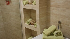 Ett badrum med tvättmaskin, hyllor med handdukar och en tvåldispenser.