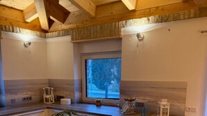 A modern kitchen with wooden beams, a window, a sink, and a potted plant. - Bungalow "Villa Toscana" with Private Terrace, Garden, and Wi-Fi (Teltow)