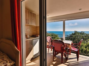 Un balcon avec une table et des chaises, une vue sur la mer et un coin cuisine.
