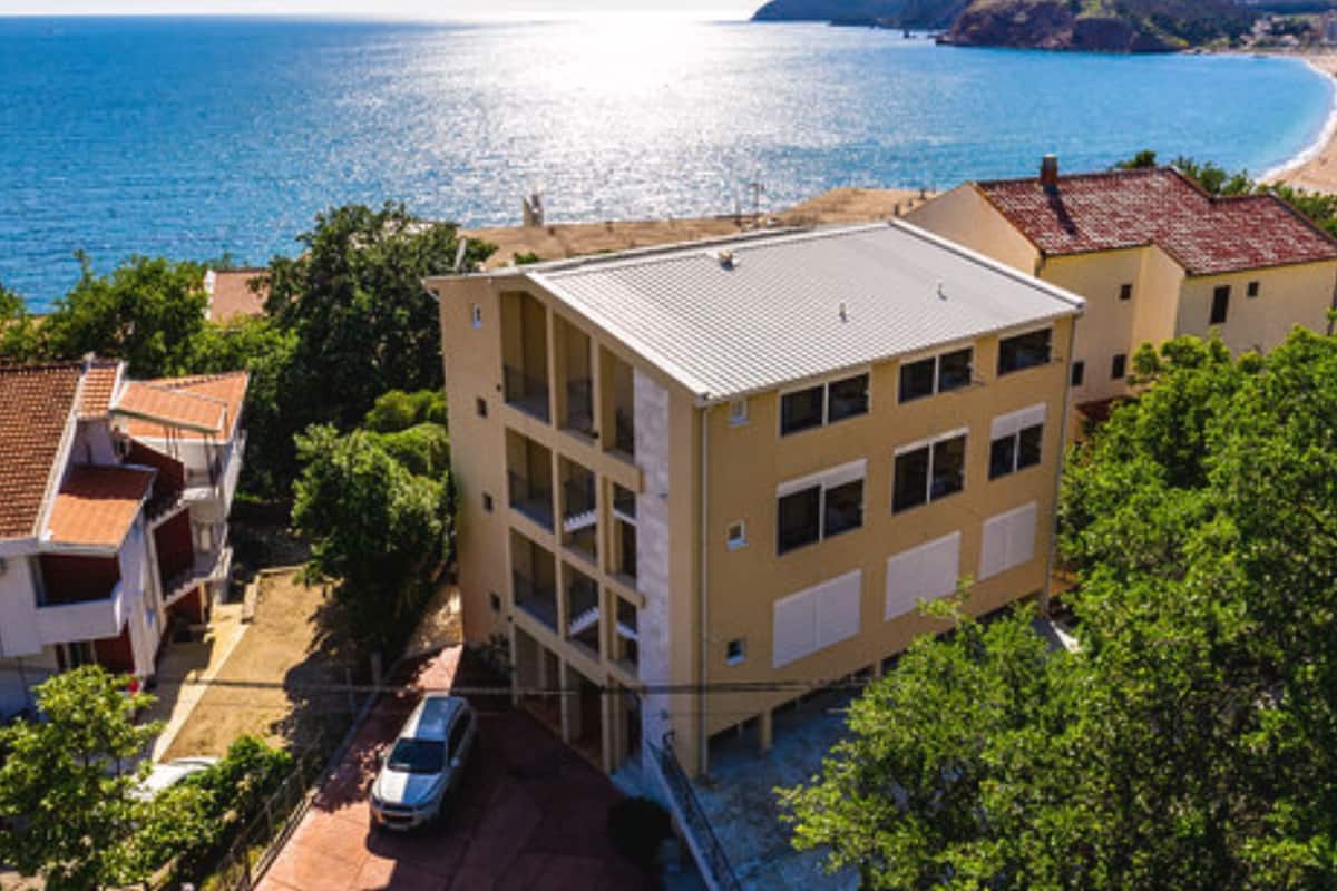 A multi-story building with a flat roof, located near a coastline.