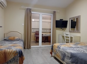 A hotel room with two beds, a desk, a chair, a TV, and a sliding door to the balcony. - Beachfront Sunset Apartments Sutomore (Sutomore)