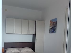 Une chambre à coucher avec un lit, une grande armoire et un tableau représentant un paysage urbain accroché au mur.