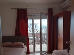A bedroom with a bed, a wardrobe, and a sliding glass door leading to an outdoor area. - Beachfront Sunset Apartments Sutomore (Sutomore)