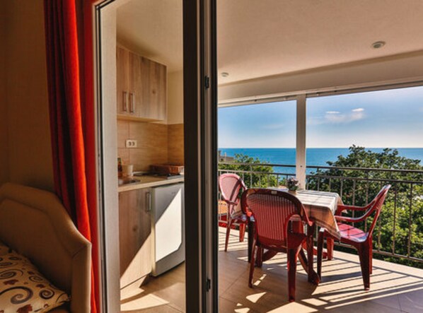 Un balcon avec une table et des chaises pour prendre les repas, un coin cuisine et une vue sur l’océan.