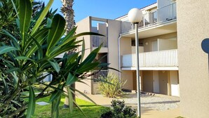 Un edificio de varios pisos con balcones y un jardín.