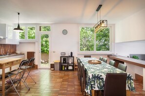 Eine moderne Küche mit Essbereich, großen Fenstern und Blick auf Grünflächen.