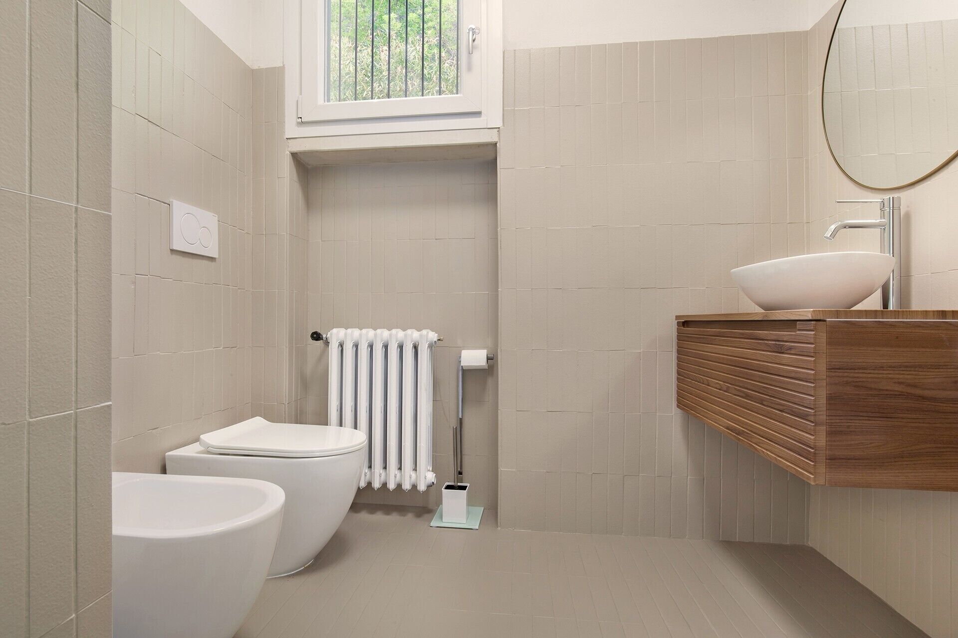 Une salle de bain moderne équipée de toilettes, d’un bidet et d’un lavabo avec un meuble-vasque en bois.