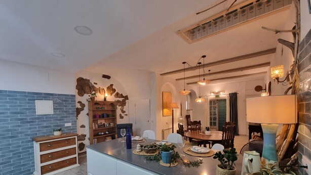 A kitchen with a central island, wooden cabinets, and a stone wall. - Charming House, 2 Bedrooms, Terrace & Air Conditioning (L'Escala)