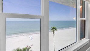Vista de una playa a través de una ventana con cielo despejado.