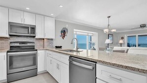 Una cocina moderna con electrodomésticos de acero inoxidable, muebles blancos y una isla grande con un fregadero.