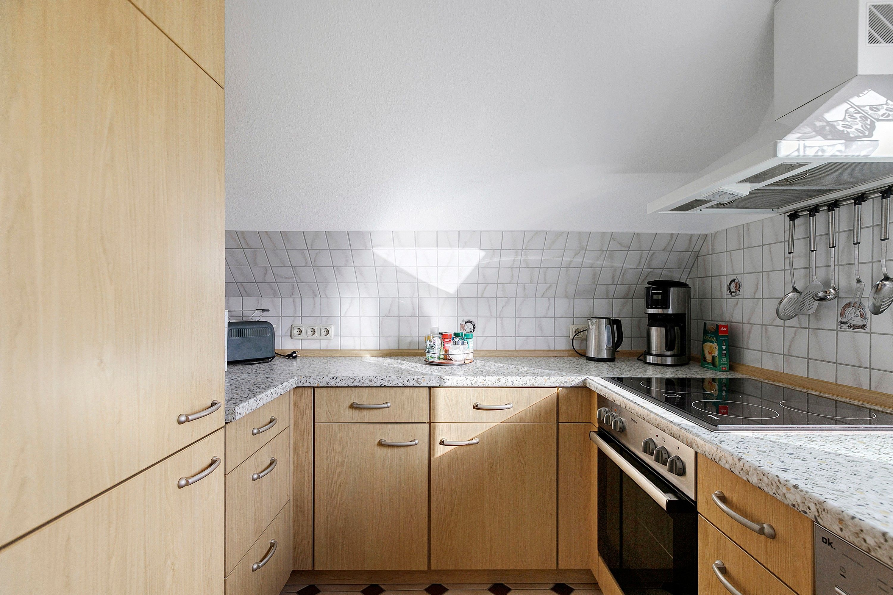 A kitchen with wooden cabinets, a granite countertop, a stove, and a coffee maker.