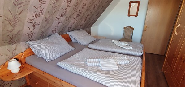 Un lit avec une literie à rayures, une tête de lit en bois, une table de chevet avec une lampe et un miroir au mur.