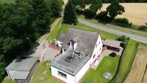 Ein zweistöckiges Gebäude mit geneigtem Dach, einer kleinen angeschlossenen Garage und einem gepflasterten Einfahrt.