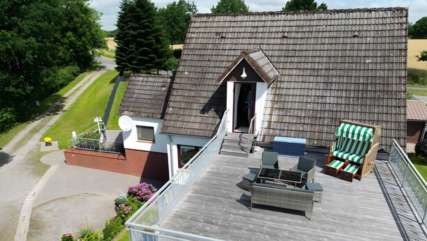 Ein Wohnhaus mit Balkon, kleinem Garten und einem Haus mit Satteldach.