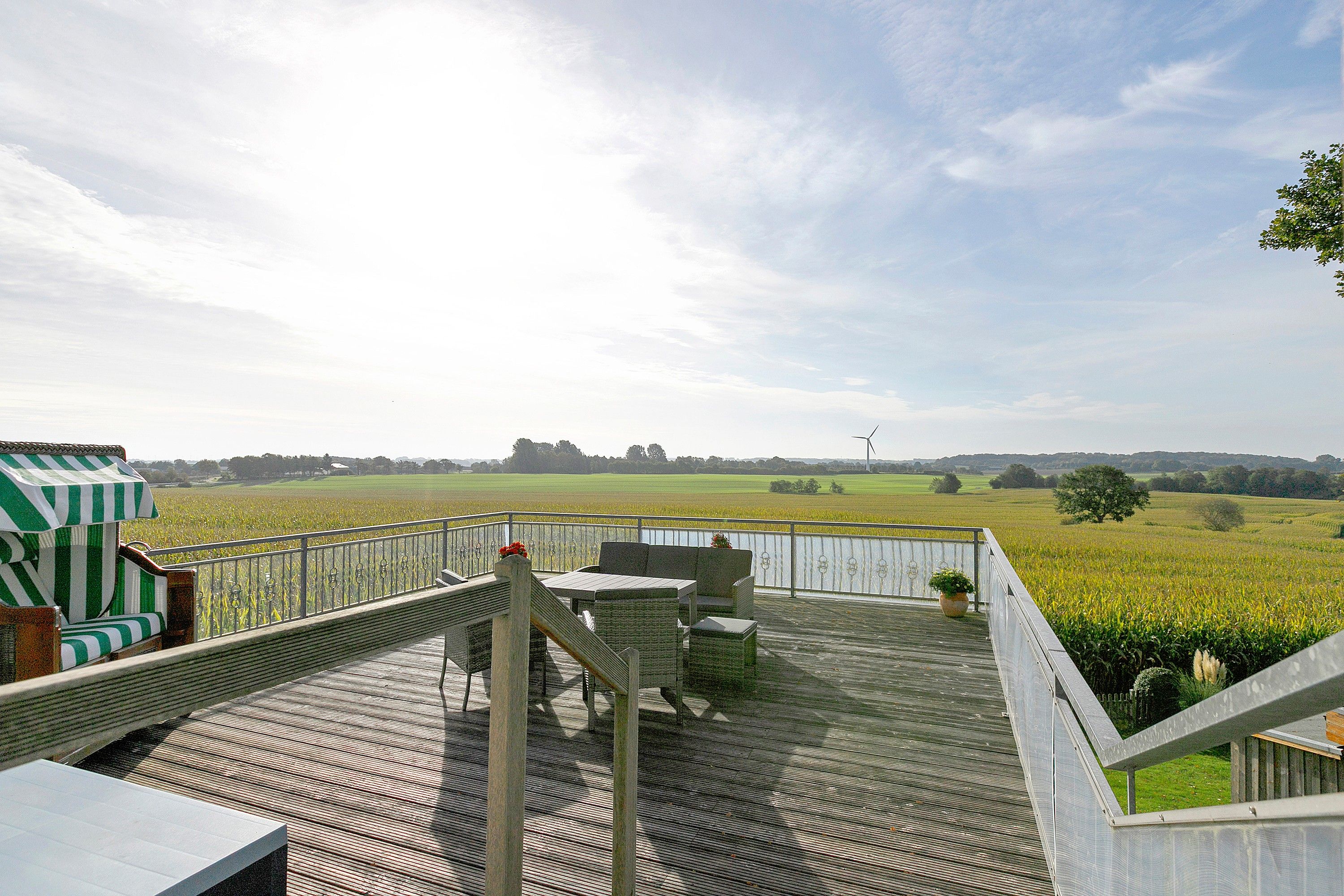 Een houten terras met tuinmeubilair met uitzicht op een veld.