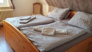 Ein Doppelbett mit gestreifter Bettwäsche und Kissen, ein hölzernes Kopfende, ein Nachttisch mit Lampe und eine Heizung.