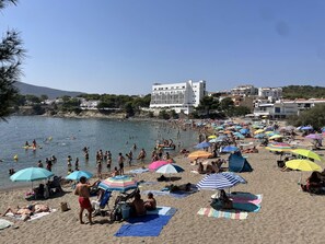 A beach with people sunbathing, swimming, and using umbrellas. - Renovated Apartment by the Sea - A/C and Pets Allowed (Llançà)