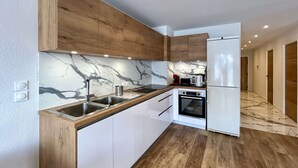 Eine moderne Küche mit Holzausstattung, einer Marmor-Spritzschutzwand und einem eingebauten Backofen.