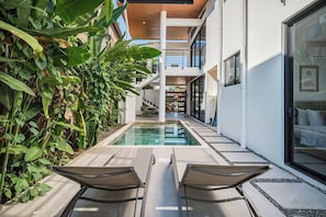A modern building with a pool, two lounge chairs, and a staircase leading to an upper level. - High Tide Hideaway (Playa Hermosa)