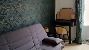 A room with a dark-colored sofa, a small table with a chair, and a patterned wall. - Modern studio with private garden - Cure thermale Saint-Honoré-les-Bains (Saint-Honoré-les-Bains)