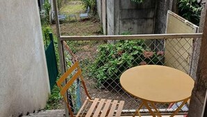 A small outdoor seating area with a table and a chair, enclosed by a metal fence. - Modern studio with private garden - Cure thermale Saint-Honoré-les-Bains (Saint-Honoré-les-Bains)