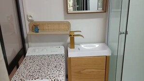 A compact bathroom with a bed, a small sink, and a mirror. - Modern studio with private garden - Cure thermale Saint-Honoré-les-Bains (Saint-Honoré-les-Bains)