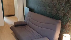 A modern living room with a grey sofa, a wooden wardrobe, and a patterned wall. - Modern studio with private garden - Cure thermale Saint-Honoré-les-Bains (Saint-Honoré-les-Bains)