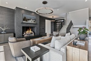 A modern living room with a fireplace, a sofa set, a coffee table, and a staircase leading to an upper level. - Spacious Ski Getaway Hot Tub 5 Bedroom 5 Home (Heber City)